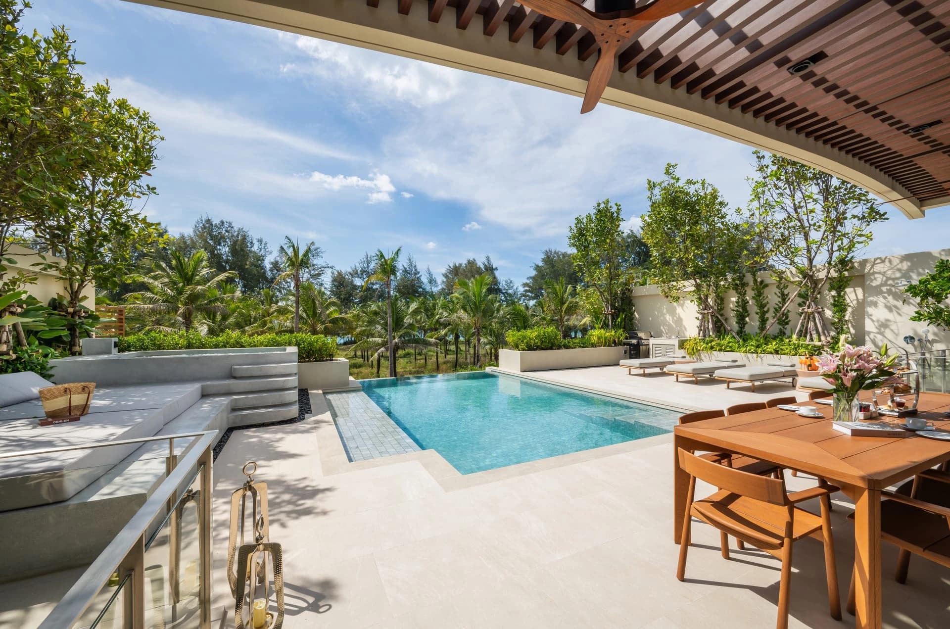 Built: the upper terrace of a finished Aegir villa with the dining table, the pool and the casuarina trees